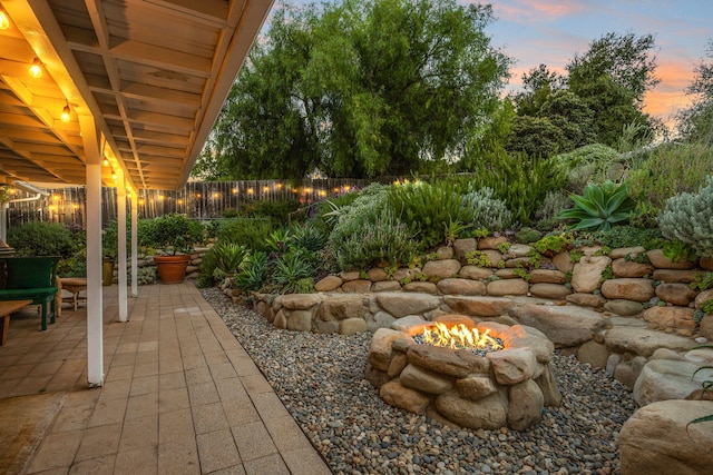 yard at dusk with a fenced backyard, a patio, and an outdoor fire pit