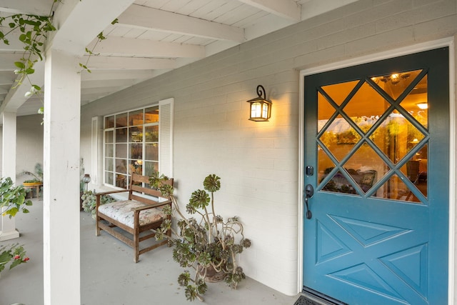 view of exterior entry featuring concrete block siding and a porch