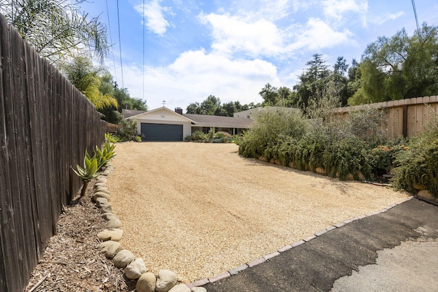 view of yard with a garage, driveway, and fence