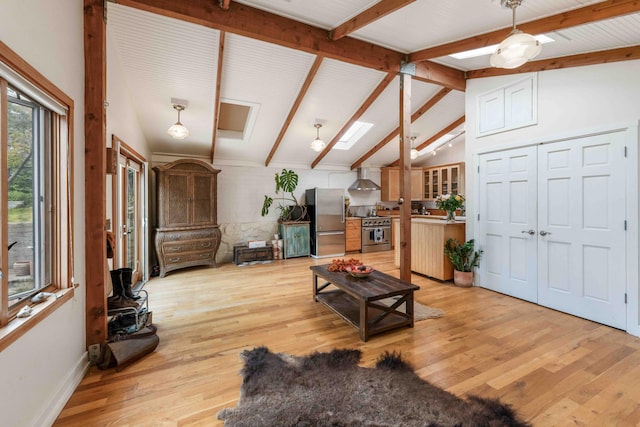 living area featuring light wood-style flooring, vaulted ceiling with beams, and baseboards
