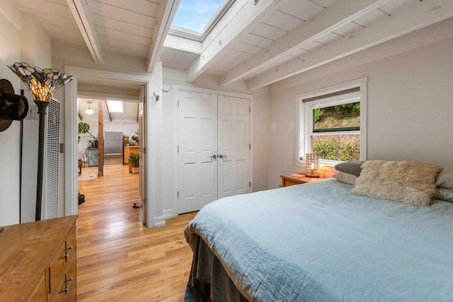 bedroom featuring light wood-type flooring, beamed ceiling, and a skylight