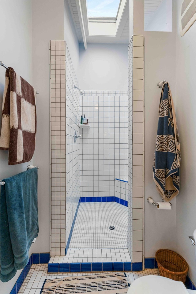 full bath featuring a skylight, toilet, tile patterned flooring, and a stall shower