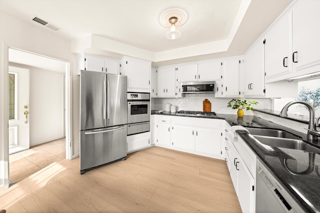 kitchen featuring visible vents, a sink, appliances with stainless steel finishes, white cabinetry, and decorative backsplash