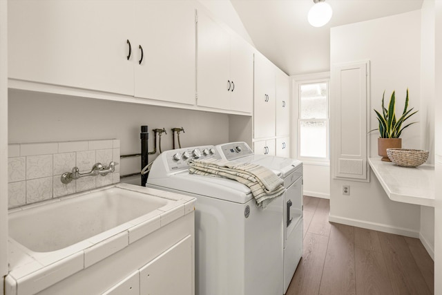 laundry area with baseboards, a sink, wood finished floors, cabinet space, and washer and clothes dryer