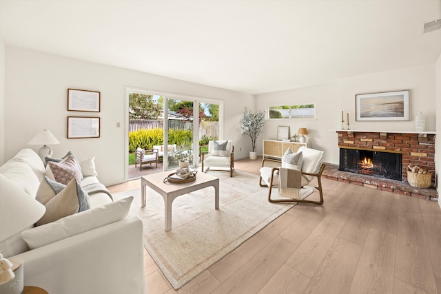 living area featuring light wood-style floors, a fireplace, and visible vents
