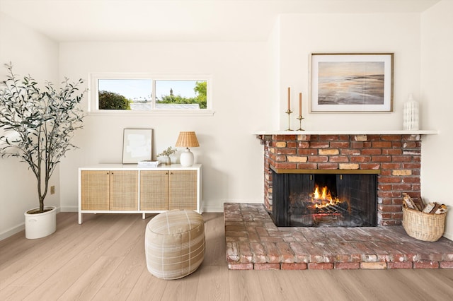 sitting room with a fireplace, baseboards, and wood finished floors