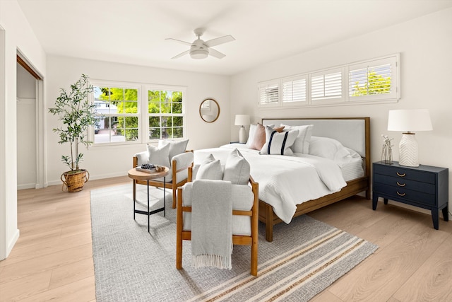 bedroom with light wood-type flooring, baseboards, and a ceiling fan