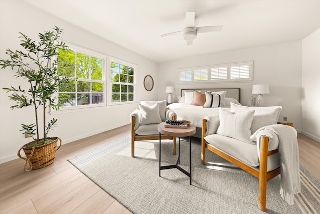 bedroom with baseboards, multiple windows, ceiling fan, and light wood finished floors