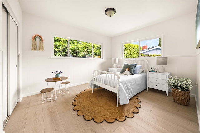 bedroom featuring wood finished floors, a wainscoted wall, and a decorative wall