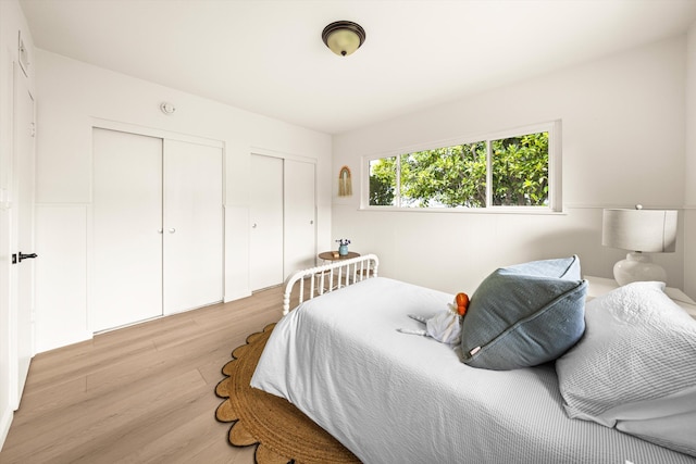bedroom with light wood-style flooring and two closets