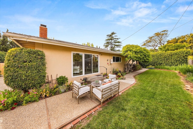 back of property with a yard, a chimney, a patio, and stucco siding