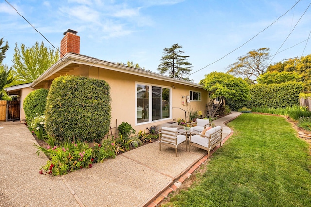 rear view of property featuring a yard, stucco siding, a patio, fence, and a chimney