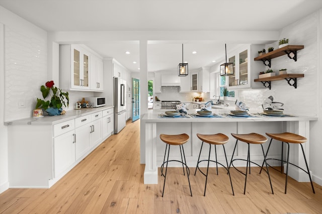 kitchen with a peninsula, high end appliances, backsplash, and a breakfast bar area