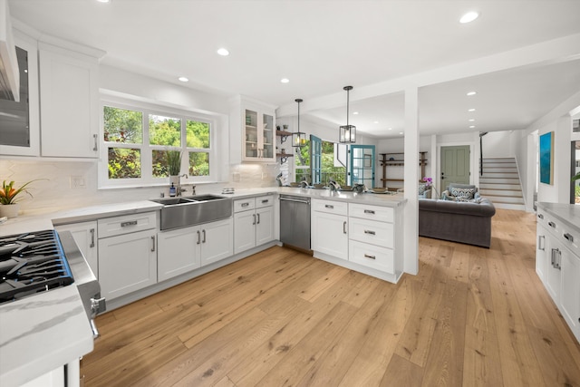 kitchen with a sink, open floor plan, dishwasher, backsplash, and a peninsula
