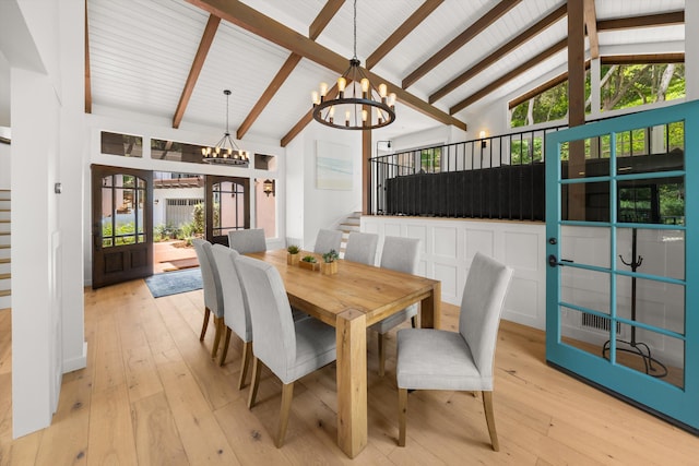 dining room featuring beam ceiling, light wood-type flooring, a notable chandelier, stairs, and high vaulted ceiling