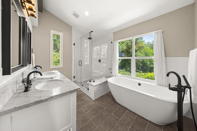 full bathroom with a shower stall, double vanity, visible vents, a sink, and a soaking tub