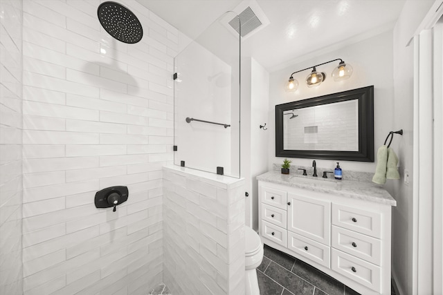 bathroom featuring tile patterned floors, toilet, a tile shower, visible vents, and vanity