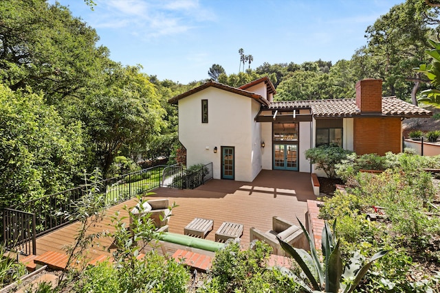 rear view of property with a wooden deck, a tiled roof, french doors, and stucco siding
