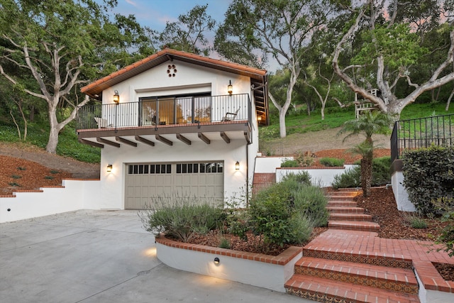 mediterranean / spanish-style house with stairway, a balcony, driveway, a garage, and stucco siding