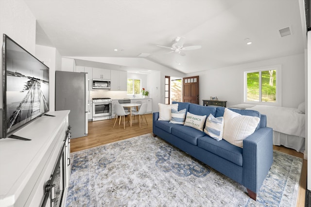 living room with vaulted ceiling, ceiling fan, light wood-style flooring, visible vents, and recessed lighting