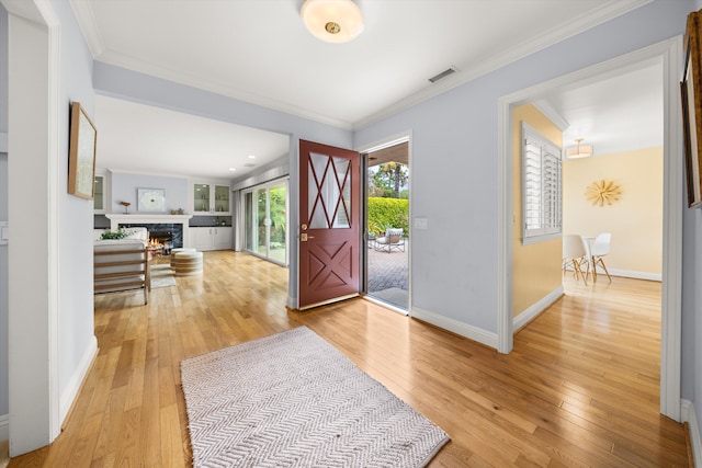 foyer featuring crown molding, baseboards, and light wood-type flooring