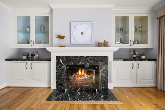 bar featuring a fireplace, a bar, and light wood-style flooring