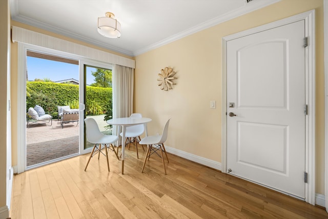 dining room with crown molding, baseboards, and light wood-style flooring