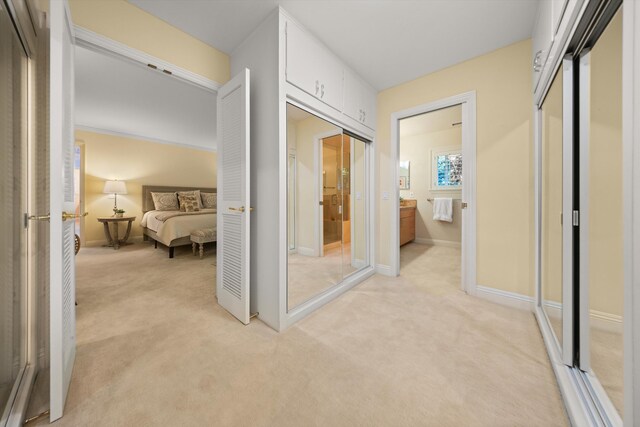 hallway featuring baseboards and light carpet