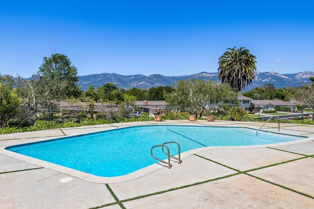 pool with a patio area, a mountain view, and fence