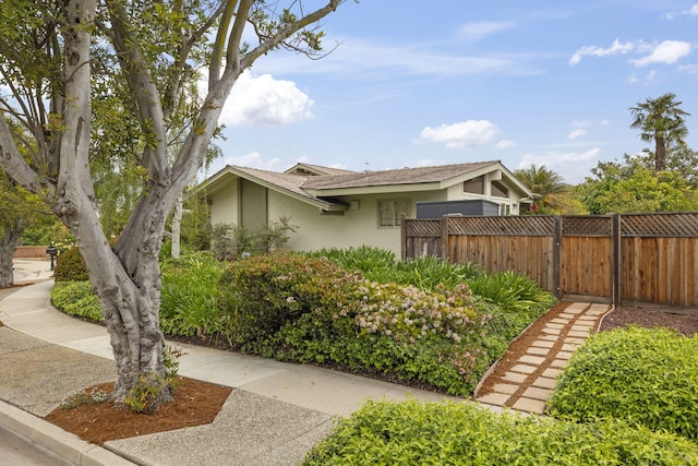 view of side of home featuring stucco siding and fence