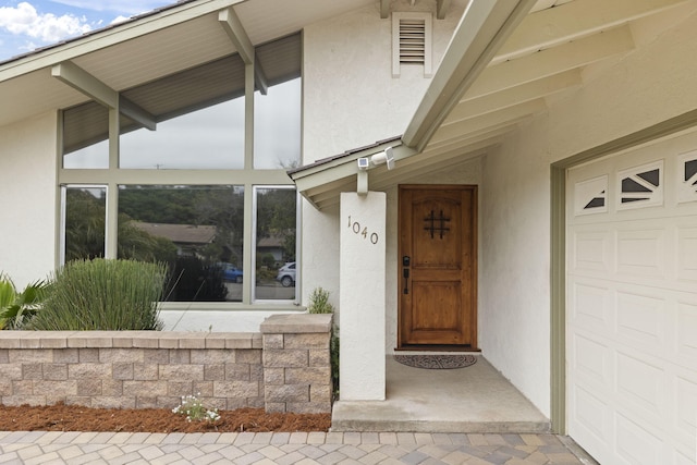 entrance to property featuring a garage and stucco siding