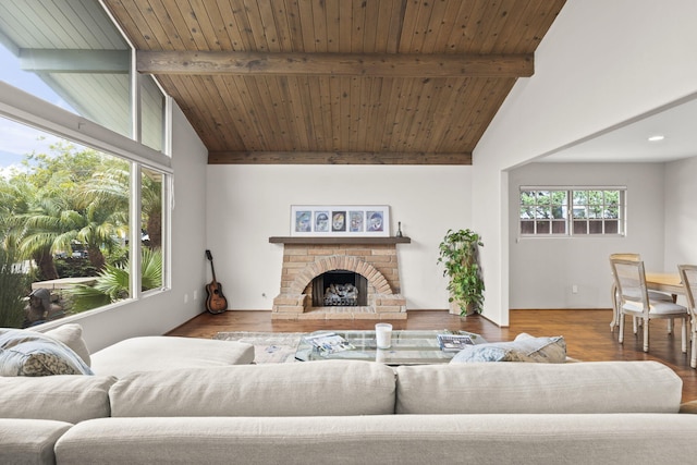 living room featuring beam ceiling, wood finished floors, wooden ceiling, a stone fireplace, and high vaulted ceiling
