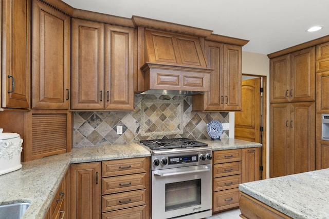 kitchen featuring brown cabinets, stainless steel gas range, and light stone countertops