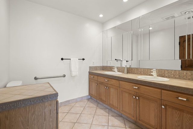 bathroom with baseboards, tile patterned flooring, a sink, and double vanity
