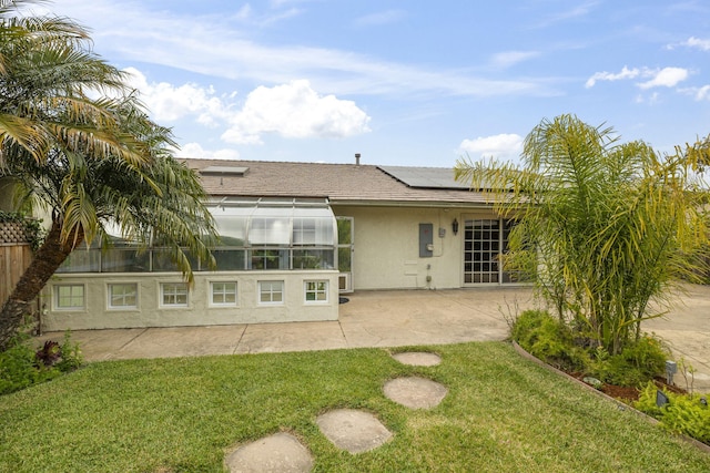 back of property featuring solar panels, a patio area, a lawn, and stucco siding