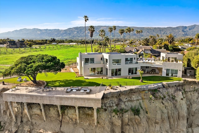 rear view of property featuring a fenced backyard, a mountain view, a yard, a patio, and stucco siding