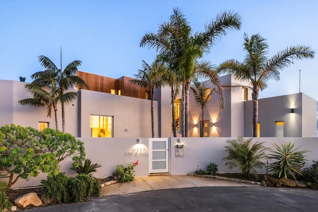 view of front facade featuring stucco siding and fence