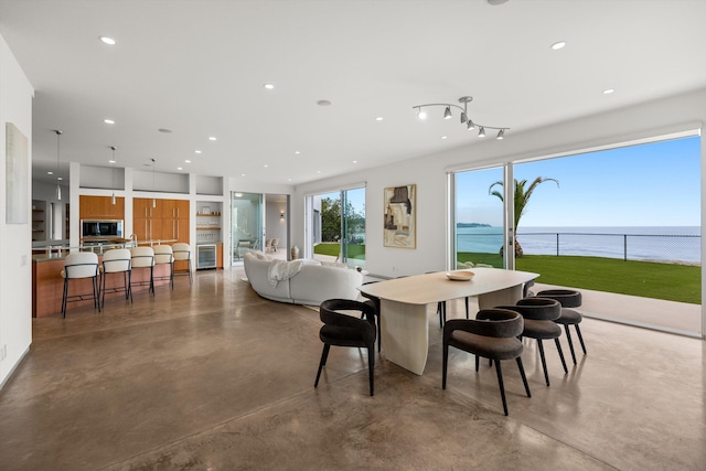 dining area featuring recessed lighting, a water view, and finished concrete flooring