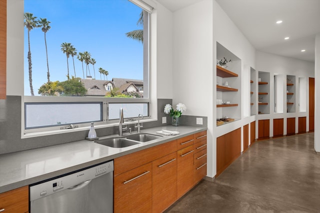 kitchen with brown cabinetry, stainless steel dishwasher, concrete flooring, and a sink