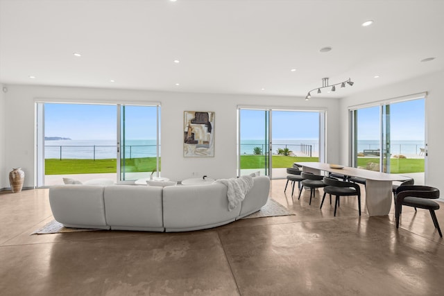 living room with concrete floors, a water view, recessed lighting, and a healthy amount of sunlight