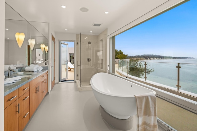 bathroom featuring a stall shower, a freestanding tub, a water view, double vanity, and visible vents