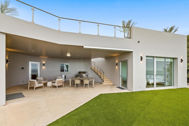 rear view of house featuring outdoor lounge area, area for grilling, stucco siding, a patio area, and a lawn