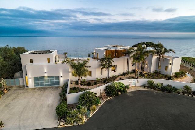 view of front of property featuring a water view, a gate, fence, concrete driveway, and stucco siding