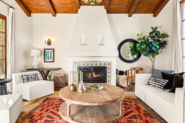 living room with wood ceiling, dark wood finished floors, vaulted ceiling with beams, and a tiled fireplace