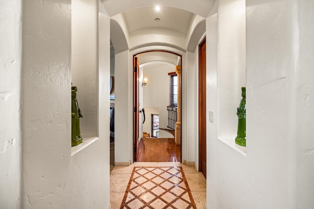 hallway featuring baseboards and arched walkways