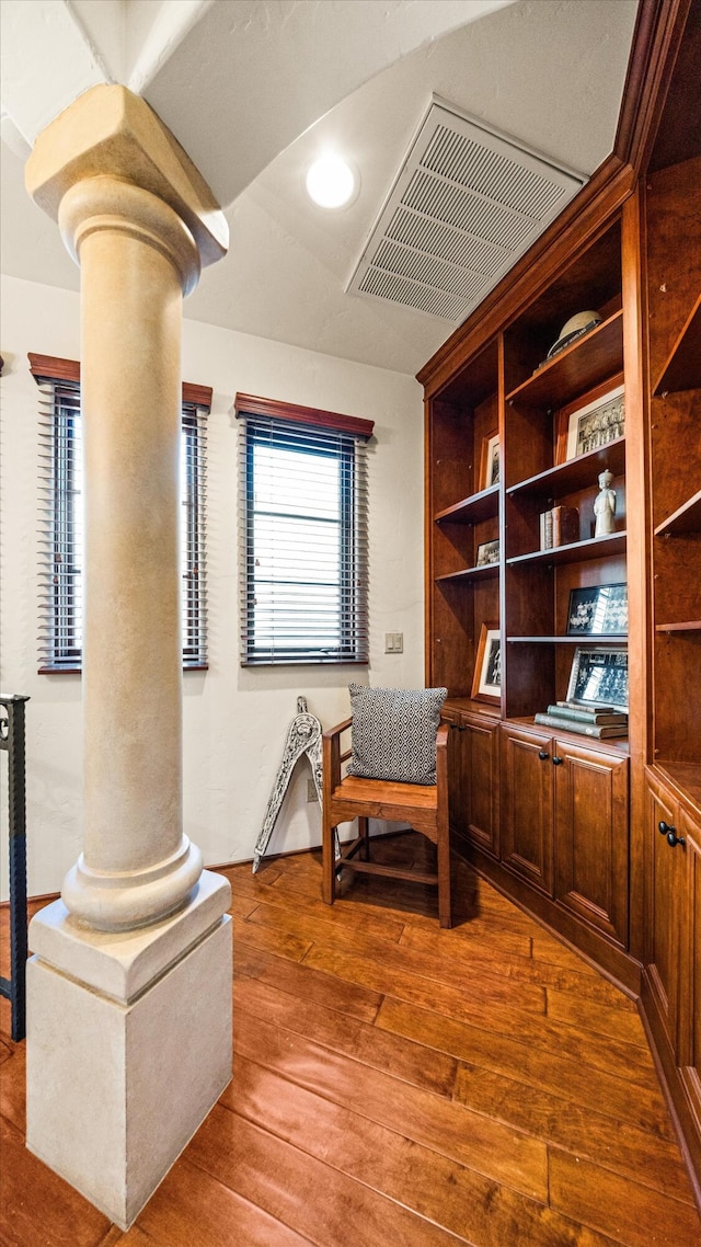 sitting room featuring hardwood / wood-style flooring, visible vents, and ornate columns