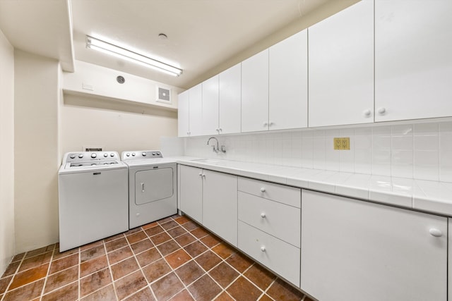 washroom featuring washing machine and dryer, visible vents, cabinet space, and a sink