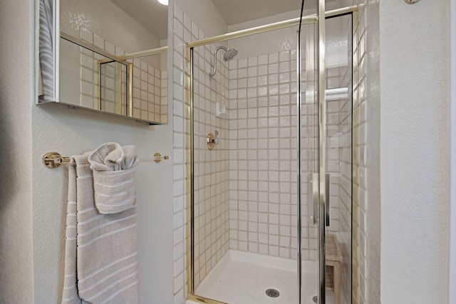 bathroom with a shower stall and a textured wall