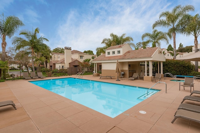 pool featuring an outdoor structure, fence, and a patio area
