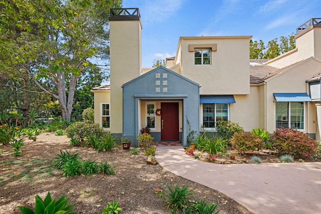 bungalow-style home with a tiled roof, a chimney, and stucco siding